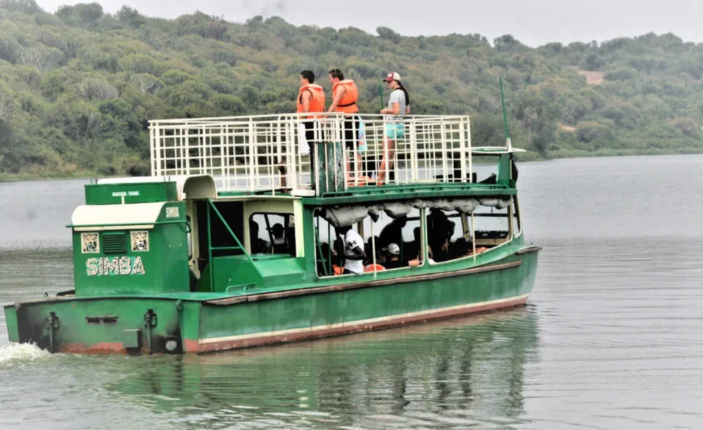 Travelers enjoying a scenic boat cruise on the Kazinga Channel with wildlife along the banks