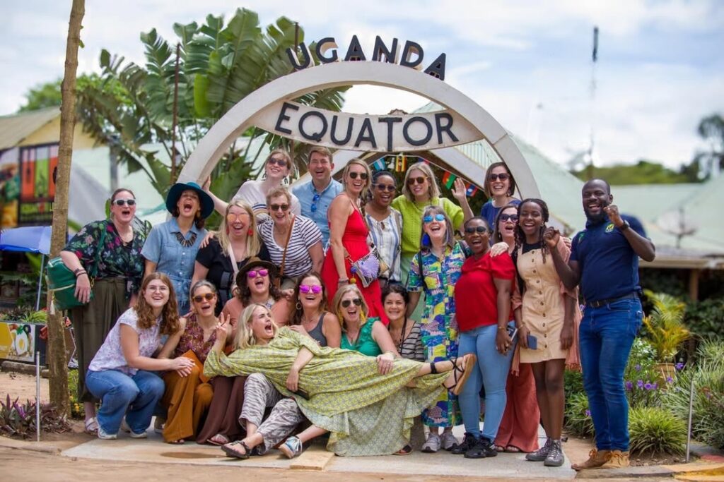 Group of tourists taking photos at the Uganda Equator landmark with the iconic circular sign in the background
