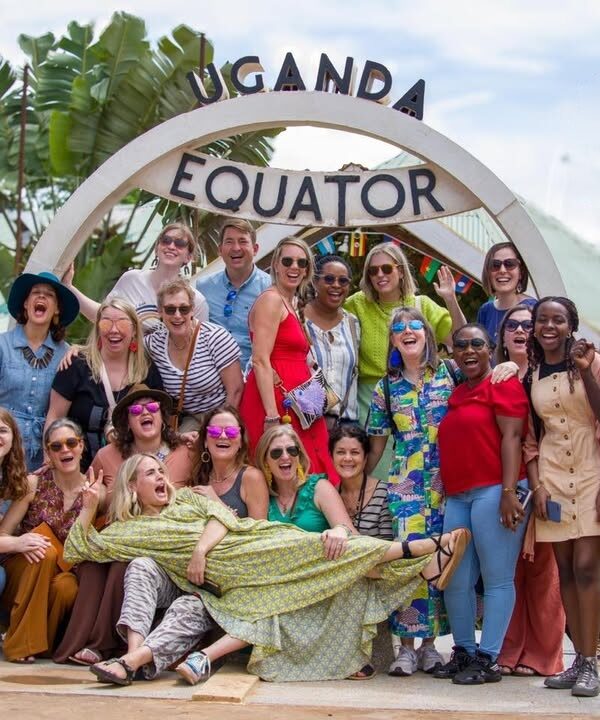 Group of tourists taking photos at the Uganda Equator landmark with the iconic circular sign in the background