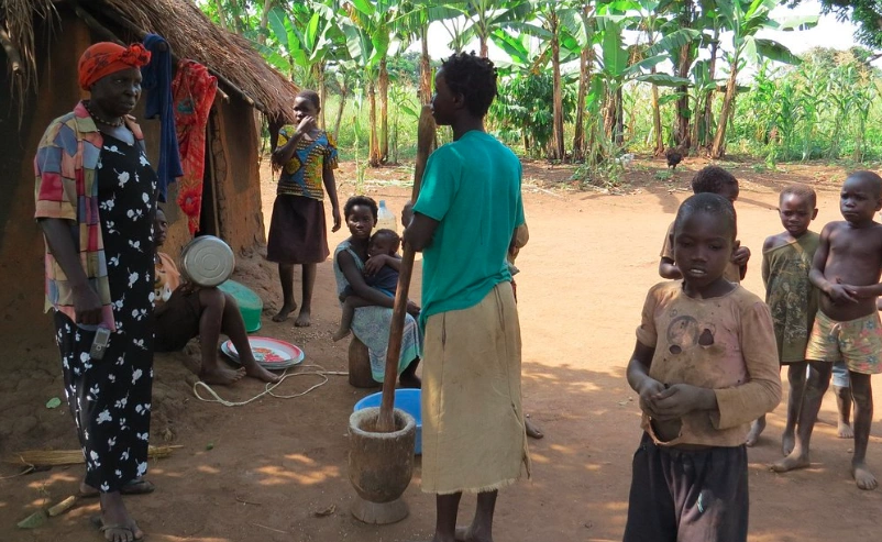 Local children and community members near Boomu Women’s Group, smiling outside traditional huts in a village setting.