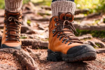Close-up of sturdy hiking boots trekking through muddy forest trail in Uganda’s jungle