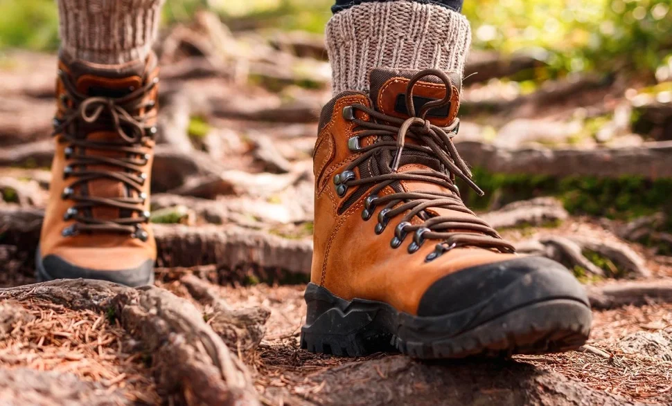 Close-up of sturdy hiking boots trekking through muddy forest trail in Uganda’s jungle