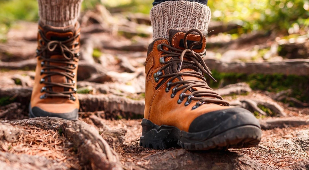 Close-up of sturdy hiking boots trekking through muddy forest trail in Uganda’s jungle