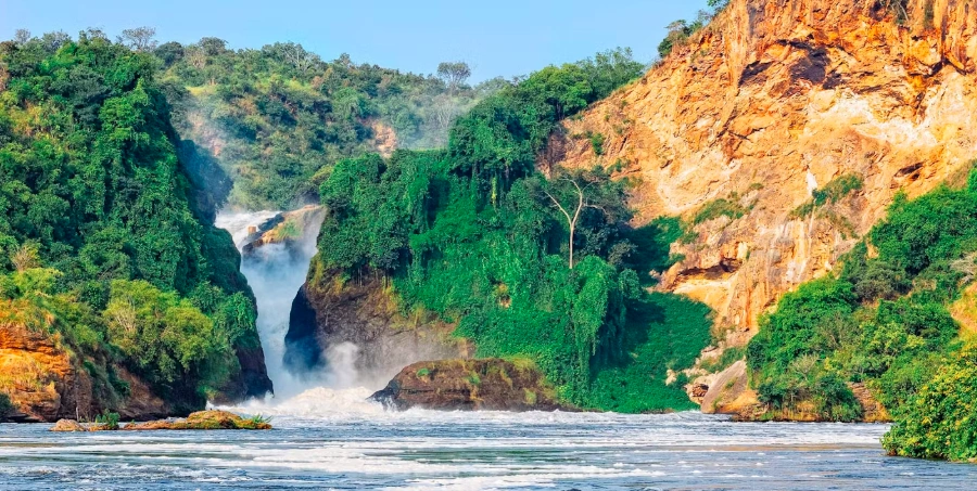Powerful Murchison Falls viewed from below during a boat cruise, with foaming white water crashing through the gorge.