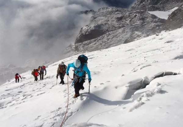 People climbing a snow-covered mountain peak in Rwenzori Mountains National Park.