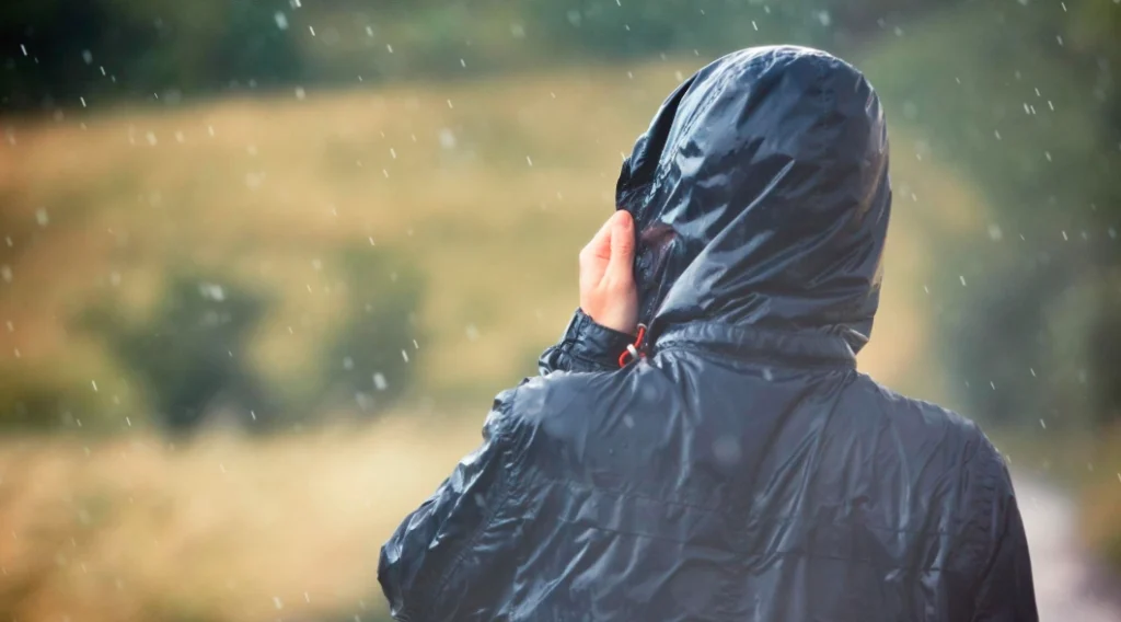 Trekker wearing a waterproof jacket walking through rain during a gorilla trek in Uganda