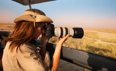 Woman photographing wildlife from safari van, highlighting gear essentials for Uganda adventures